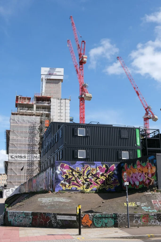 Bâtiment en conteneurs sur plusieurs niveaux et grues de chantier