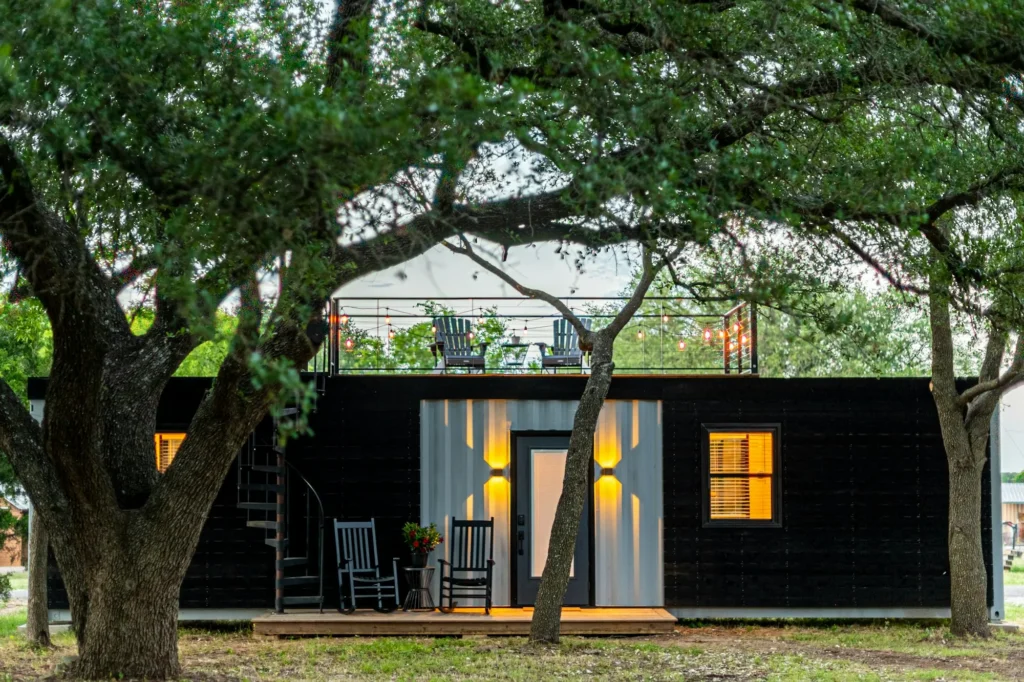 Maison container noire avec toit-terrasse sous les arbres