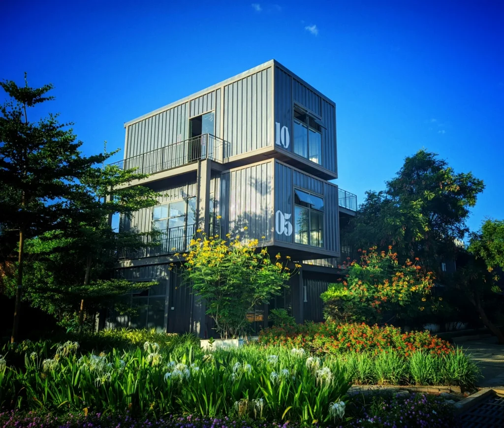 Maison en conteneurs maritimes empilés sur trois niveaux dans un jardin tropical