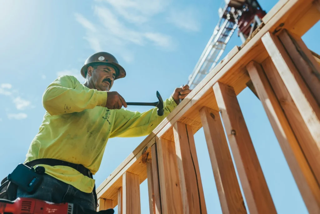 Charpentier fixant un mur à ossature bois sur un chantier de construction bois