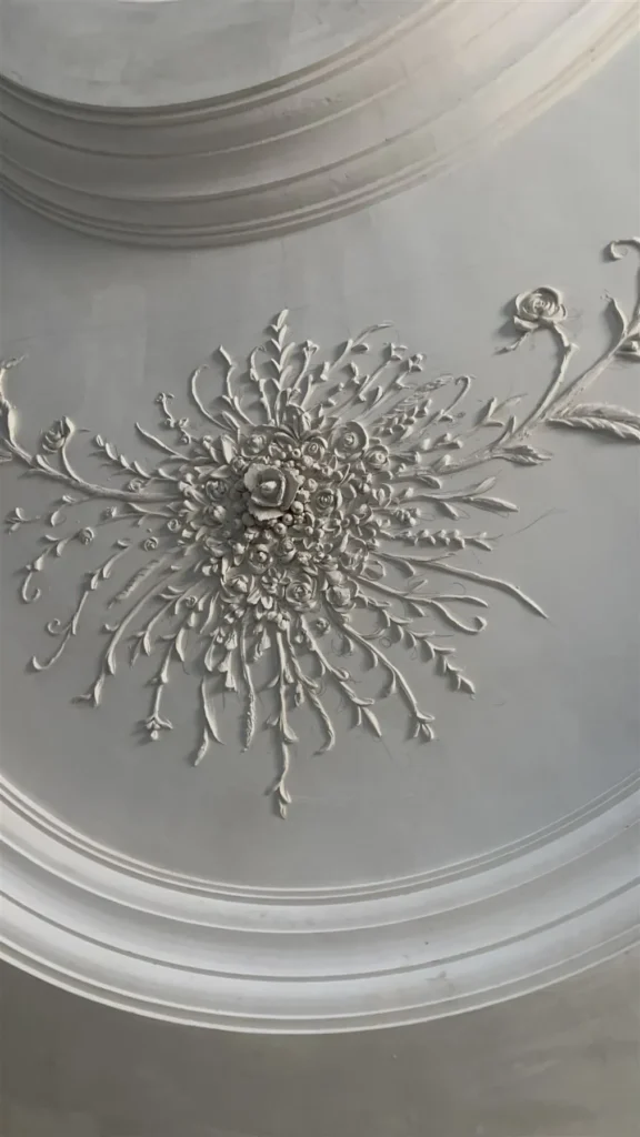 Rosace en staff sculptée au centre d’un faux plafond à gorges